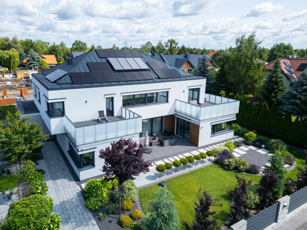 Modern white residential home with rooftop solar panels and landscaped garden